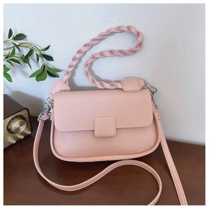 Detail of pink crossbody bag with textured leather, woven handle and square buckle