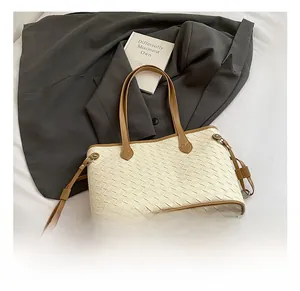 Detail of woven tote bag with beige weave texture and brown faux leather trim finish