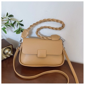 Detail of khaki crossbody bag featuring braided handle and textured lychee pattern leather