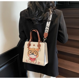 Detail of a beige tote bag featuring cute cartoon print and stylish wide patterned strap