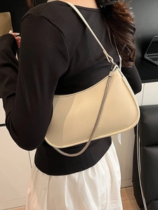 Chic cream leather underarm bag with silver chain strap shown on a female model