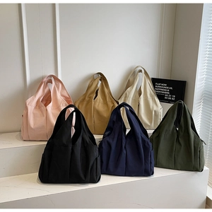 Row of minimalist fabric tote bags in six colors displayed on a white tiered stand