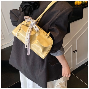Close-up of cream rectangular shoulder bag featuring dual pockets and decorative ribbon