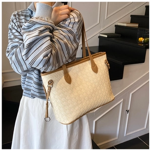 Detail view of cream woven tote bag featuring checkered texture and brown leather strap