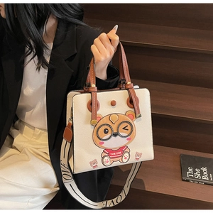 Detail of cream tote bag with bear embroidery and wide lettered shoulder strap