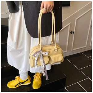 Detail of a yellow retro pillow bag featuring twin pockets and a checkered bow ribbon