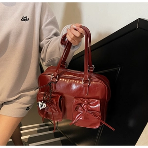 Dettaglio di uno zaino bordeaux stile balletcore con fiocchi e ciondolo a cuore