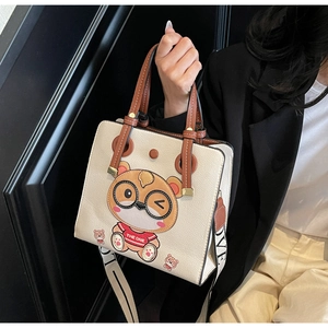 Detail of cream tote bag featuring a cartoon bear print and stylish wide shoulder strap