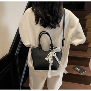 Détail du sac cabas en cuir grainé noir avec nœud en dentelle perlée et bandoulière