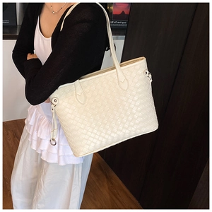 Close-up of cream woven tote bag with slim shoulder straps and metallic D-ring details