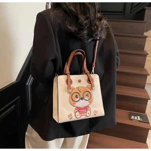 Detail of a cream faux-leather tote bag with bear print and brown shoulder strap
