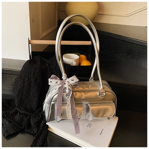 Detailed close-up of a metallic silver Boston bag with decorative dark plaid ribbon bow
