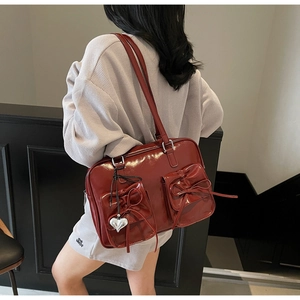 Zaino in pelle verniciata rosso scuro con fiocchi e ciondolo a cuore su modella