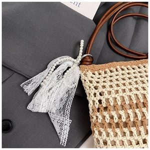 Détails de sac à bandoulière tissé avec nœud en dentelle et ornements en perles