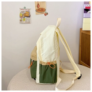 Detail of color-block nylon backpack featuring drawstring side pockets and adjustable straps
