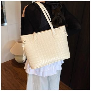 Detail of cream woven leather tote bag showing intricate texture and slim shoulder straps