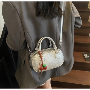 Silver mini boston crossbody bag with metallic texture and cherry charm accessory