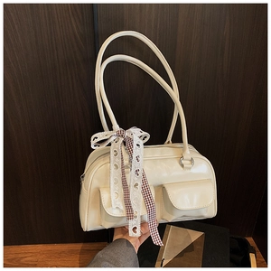 Detail of cream beige pillow bag featuring front flap pockets and a plaid lace bow
