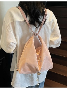 Pink satin tote bag with chain decor and pearl butterfly pendant on wooden stairs