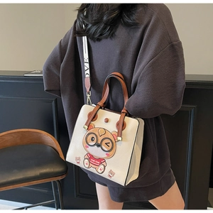Close-up of beige leather tote with cartoon bear print and LOVE lettered shoulder strap