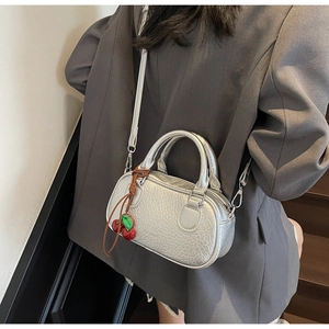 Silver crocodile textured mini bowling bag with cherry charm shown on model's shoulder