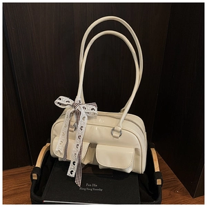 Detail of a retro cream leather Boston bag with a checkered lace bow on a vintage book