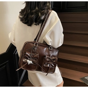 Vista dettagliata della borsa in pelle lucida marrone cioccolato con tasche a fiocco e cuore
