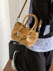 Sac seau marron chaud avec boucle métallique porté en bandoulière par un mannequin