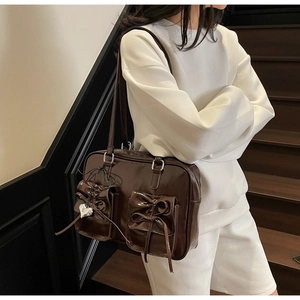 Dettaglio dello zaino in vernice marrone scuro stile balletto con fiocchi e ciondolo a cuore