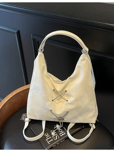 White nylon shoulder bag with silver butterfly charm and pearl details on a vintage chair