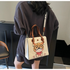 Detail of a beige tote bag with cute bear embroidery and a wide fabric LOVE strap