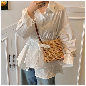 Vue détaillée du sac bandoulière en paille avec nœud en dentelle blanche et cuir brun