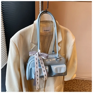 Detail of light blue patent leather shoulder bag with pockets and plaid ribbon decoration