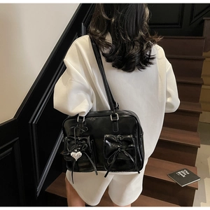 Dettaglio borsa nera stile balletto con fiocchi decorativi e ciondolo a cuore argento