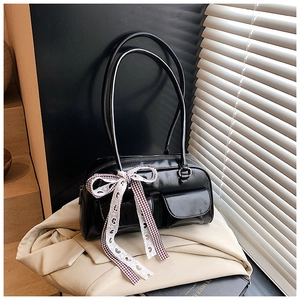 Close-up of black shoulder bag with red plaid bow and white heart ribbon detail