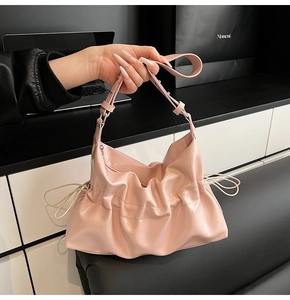 Détail de sac hobo plissé rose avec cordon de serrage et texture en similicuir souple