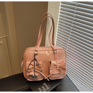 Dettaglio borsa rosa in vernice lucida con tasche a fiocco e ciondolo a cuore