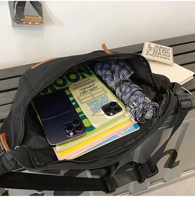 Vue de dessus du grand sac bandoulière en toile noire montrant sa grande capacité de rangement