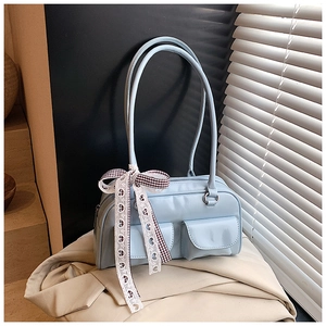 Detail of light blue rectangle shoulder bag with flap pockets and decorative heart ribbon