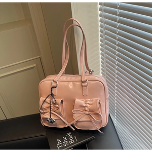 Dettaglio dello zaino rosa chiaro stile balletto con tasche a fiocco e ciondolo a cuore