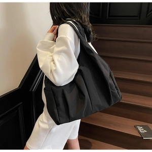 Détail d'un grand sac cabas plissé noir montrant sa capacité et sa poche latérale