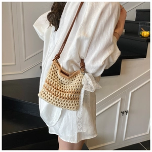 Détail d'un sac tissé au crochet avec dégradé de couleurs et nœud en dentelle blanche