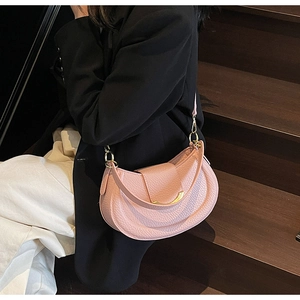 Detail of pink saddle bag with litchi grain texture and gold metal buckle on stairs