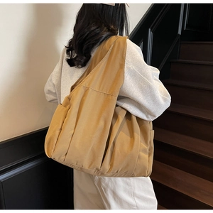 Macro detail of mustard yellow pleated tote bag showing large capacity and side pocket