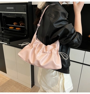 Gros plan d'un sac hobo plissé rose pâle avec finition brillante et cordon de serrage
