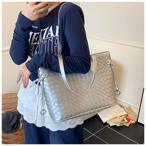 Detailed view of large silver woven tote bag on shoulder for daily office commute
