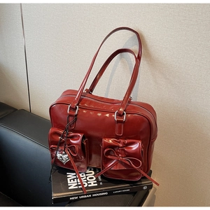 Dettaglio dello zaino in pelle lucida rosso scuro con fiocchi decorativi e stile retrò
