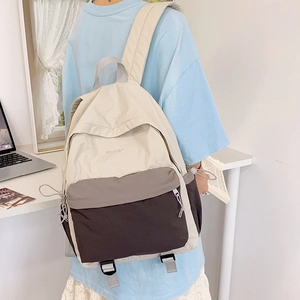 Detail of color-block nylon backpack featuring beige, grey, and brown textured panels
