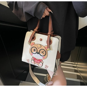 Close-up of beige leather tote bag with a cute cartoon bear print and wide strap
