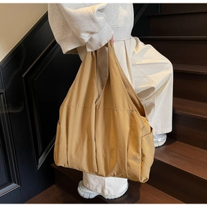 Vue latérale d'un grand sac cabas en toile kaki porté par un mannequin dans un escalier